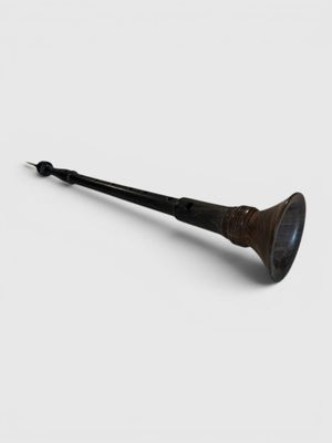 an old pipe is sitting on a white surface with a black handle