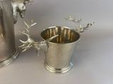 a silver cup with a deer head on it next to a silver cup with a deer head on it