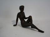 une statue représentant un homme assis sur une surface blanche