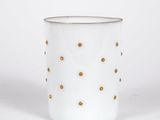 a close up of a white cup with gold dots on it