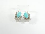 une paire de boucles d'oreilles en turquoise et argent posées sur un fond blanc