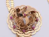 a gold necklace with pink stones on a white surface