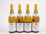 quatre bouteilles de vin sont alignées sur une surface blanche
