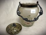 a small vase with a lid sitting next to a small container