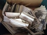 a cardboard box full of old photos and papers
