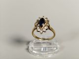 gros plan d'une bague en or avec un saphir et des diamants
