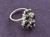 a close up of a silver ring with blue stones on a purple surface