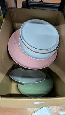 de nombreuses assiettes dans une boîte en carton posée par terre