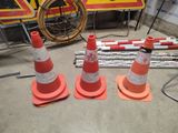 several orange and white traffic cones sitting on top of a cement floor