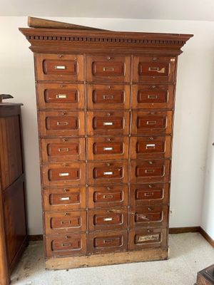 a tall wooden cabinet with many drawers in it