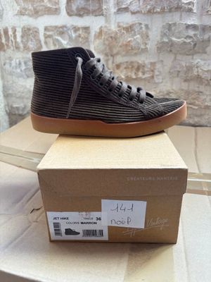 black and brown high top sneakers on top of a cardboard box