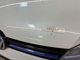 the front end of a white car with a sticker on it ' s hood