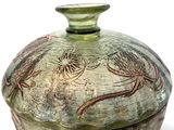 a green vase with a lid that has a design on it
