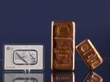 trois types différents de lingots d'or posés sur une table en verre