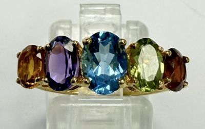 une photo en gros plan d'une bague ornée de trois pierres de couleurs différentes