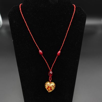 un collier orné d'une perle rouge et d'un cœur doré