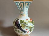 a small vase with a bird on it sitting on a table