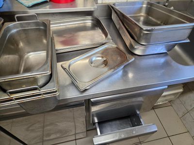 Plusieurs plats sont alignés sur un plan de travail en inox.