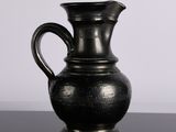 un vase noir posé sur une table, sur fond blanc
