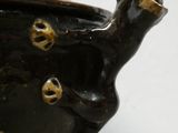 a black vase with gold decorations on it on a white surface