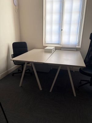 une table blanche avec une chaise noire devant une fenêtre