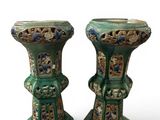 pair of green vases with floral designs on them against a white background