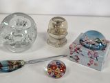trois objets en verre posés sur une table, avec une cuillère et un repose-cuillère