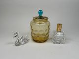 a small glass jar with a blue top next to a small glass bottle with a blue top