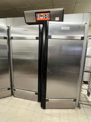Plusieurs réfrigérateurs en acier inoxydable sont alignés dans une cuisine