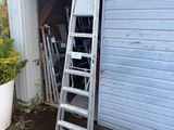 une échelle appuyée contre la porte du garage, à côté d'une plante en pot