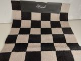 La couverture à carreaux noirs et blancs est posée sur la table.