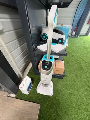 deux robots aspirateurs posés sur la pelouse devant un immeuble