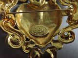 a gold brooch with a heart and two birds on it