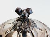 a silver plate with a lid that has a flower on it