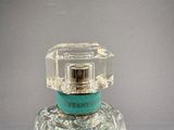 a bottle of perfume with a glass top on a table