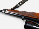 a rifle that is laying next to a knife on a table