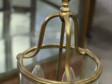 a glass and brass hanging light fixture in a room