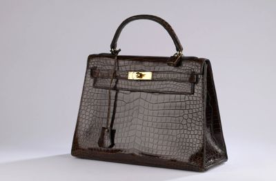 a brown crocodile skin handbag with gold hardware on a white background