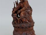 une vieille statue en bois représentant un homme assis sur une souche d'arbre