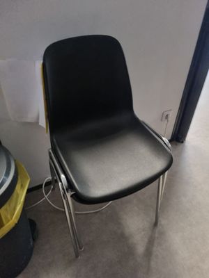 une chaise noire qui se trouve à côté d'une poubelle et d'une poubelle