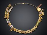 a gold necklace with various colored stones on a black background