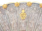a large silver fan with gold decorations on it