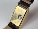 a person holding a gold watch with a brown strap