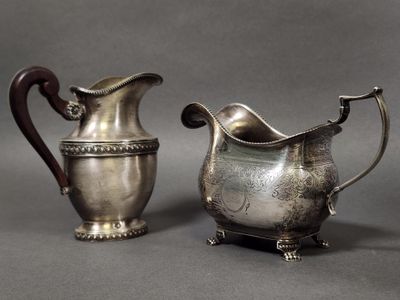 pair of antique silverplated pitchers on stand on grey background