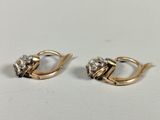 a pair of gold and diamond earrings on a white surface