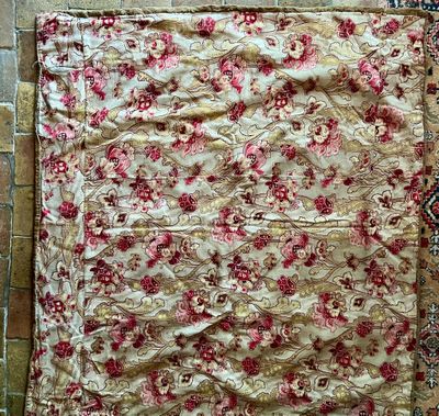 un tapis posé au sol, orné d'un motif rouge et or