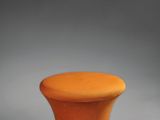 un tabouret orange posé sur une surface grise