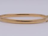 un gros plan d'un bracelet rigide en or sur fond blanc