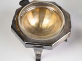 a small silver plate on a stand on a white surface