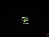 un gros plan d'une tourmaline verte posée sur une surface noire